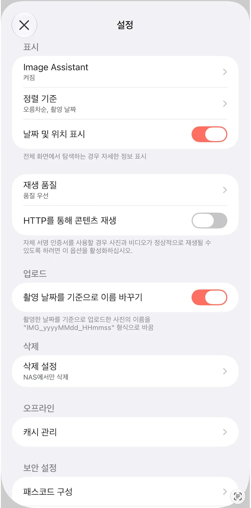 iPhone Synology Photos 앱의 설정 화면. 표시 항목에 Image Assistant 켜짐, 정렬 기준 오름차순과 촬영 날짜, 날짜 및 위치 표시 켜짐이 있고, 재생 품질은 품질 우선, HTTP를 통해 콘텐츠 재생은 꺼짐이다. 업로드 항목의 촬영 날짜를 기준으로 이름 바꾸기는 켜짐이고 설명에 IMG_yyyyMMdd_HHmmss 형식이 적혀 있다. 삭제 항목의 삭제 설정은 NAS에서만 삭제로 되어 있다. 오프라인의 캐시 관리와 보안 설정의 패스코드 구성이 아래에 있다.